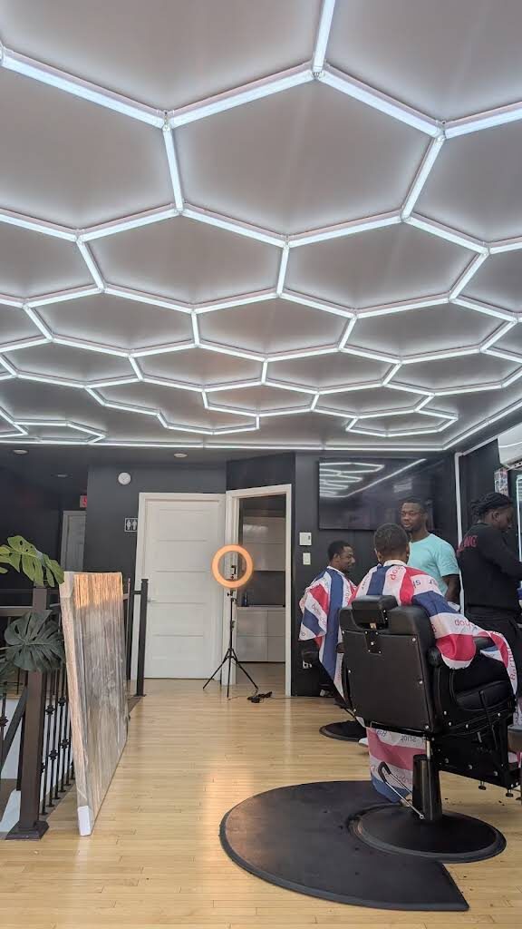 Vue d'ensemble du salon Eric Barber, plafond alvéolé lumineux et postes de coupe